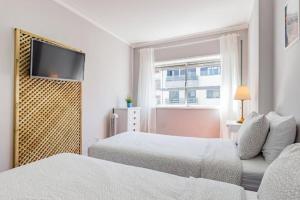 a bedroom with two beds and a flat screen tv at Apartamento Lar doce Lar Porto in Vila Nova de Gaia