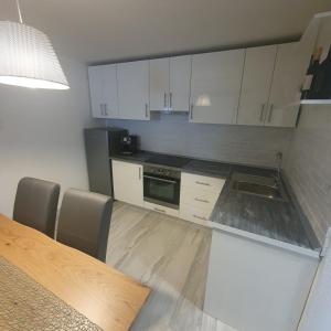 a kitchen with white cabinets and a table with chairs at Apartman Incerum in Požega