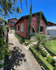 una casa roja con árboles y plantas delante de ella en Mala & Tudo Pousada, en Torres