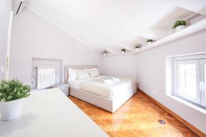 a white bedroom with a bed and a window at Penthouse in the heart of the city center in Rome