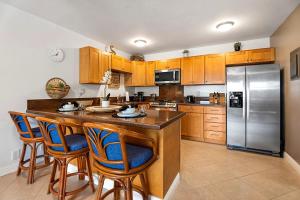a kitchen with wooden cabinets and a large island with bar chairs at Kona Bali Kai #230 in Kailua-Kona