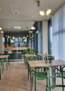 a restaurant with wooden tables and green chairs at Marida Hotel in Satu Mare