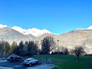 two cars parked in a parking lot with mountains in the background at Bilocale pietra e legno immerso nella natura in Morgex