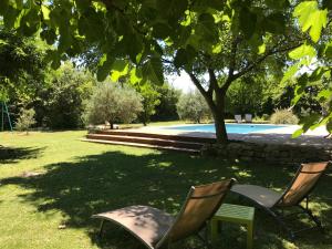 two chairs sitting under a tree near a swimming pool at L'Atelier des Coudelières in Le Thor
