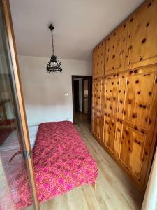 a bedroom with a pink bed and wooden cabinets at Delizioso appartamento trilocale a Moena in Moena