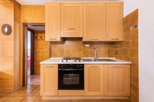 a kitchen with wooden cabinets and a black oven at Delizioso appartamento trilocale a Moena in Moena