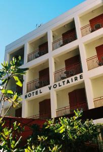 un edificio blanco con un cartel de hotel voluntario en él en Hôtel Voltaire, en Arles