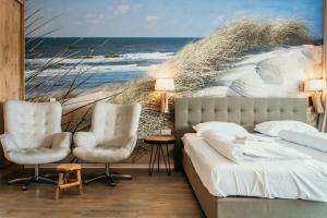 a bedroom with a bed and two chairs and the ocean at Hotel De Zeeuwse Kust (family only) in Renesse +127 photos