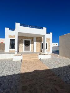 un gran edificio blanco con un cielo azul en el fondo en Magnifique villa avec piscine sur l’île de djerba, en Houmt El Souk