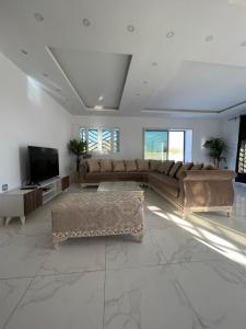 sala de estar con sofás y TV de pantalla plana. en Magnifique villa avec piscine sur l’île de djerba en Houmt El Souk