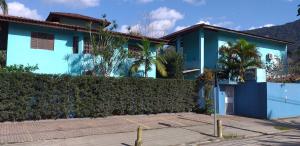 a blue house with a hedge in front of it at Atlântico in Maresias