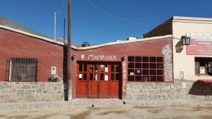 ein Backsteingebäude mit einer roten Tür auf einer Straße in der Unterkunft Hostal Mamacoca in Purmamarca