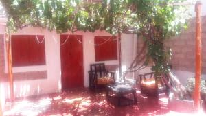 a house with red doors and chairs under a tree at Hostal Mamacoca in Purmamarca