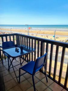 einen Tisch und Stühle auf einem Balkon mit Strand in der Unterkunft Superbe appartement vue mer 180° (wifi + parking) in Villers-sur-Mer