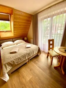 a bedroom with a bed and a table and a window at Gościniec w Zakopanem in Zakopane