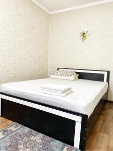 uma cama com uma moldura preta e colchão branco em Apartments Ahmetova 4 21 em Almaty