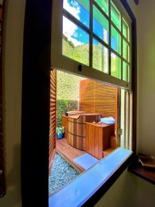 a window with a view of a patio in a house at Gaia Gardens Pousada in Paraty