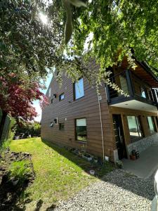 a house with a wooden facade with a yard at Espino Blanco Apartamentos in San Carlos de Bariloche