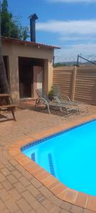 a swimming pool with two chairs next to a house at Lime Court two in Pretoria