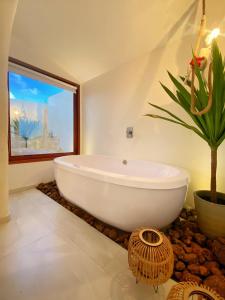 a white bath tub in a bathroom with a potted plant at Pousada Ilha do Vento in São Miguel do Gostoso