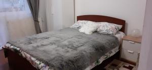 a bedroom with a bed with a gray blanket and pillows at Apartament 2 cam Predeal in Predeal
