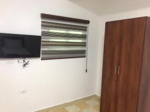 a room with a flat screen tv and a wooden cabinet at Elite Furnished Apartment in Wadi Musa