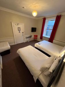 a hotel room with a bed and a television at Lost Guest House Peterhead in Peterhead