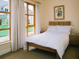 a bedroom with a white bed and two windows at Heyward Mews Holiday Homes in Swords