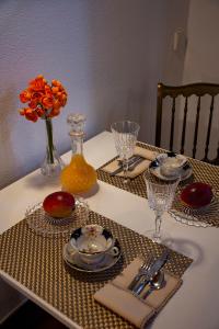 una mesa con platos y vasos y un jarrón con flores naranjas en À dos Reis en Faro