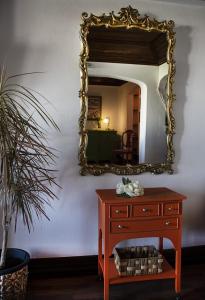 un miroir sur un mur avec une commode et une table dans l'établissement À dos Reis, à Faro