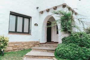 a white house with an archway and a door at Anden Espejo in Mendoza