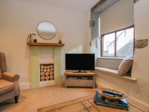 een woonkamer met een televisie en een open haard bij Kendal Cottage in Kendal