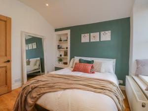 sypialnia z dużym łóżkiem i zieloną ścianą w obiekcie Kendal Cottage w mieście Kendal