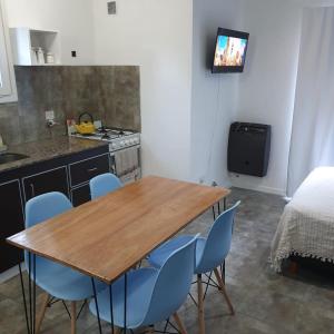cocina con mesa de madera y sillas azules en Ojo de Agua Mono, en San Martín de los Andes
