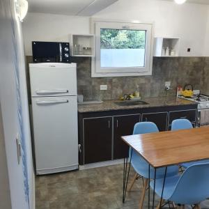 Una cocina con un refrigerador blanco y una mesa. en Ojo de Agua Mono, en San Martín de los Andes