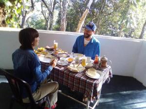 a man and a woman sitting at a table with food at New Mount Villa in Ella