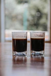 two glasses of coffee sitting on a wooden table at Jasmine House in Amirim