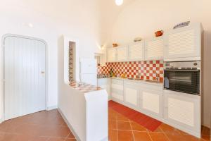 a white kitchen with orange and white tiles on the wall at TORRETTA CORRICELLA- Punta dei Monaci in Procida