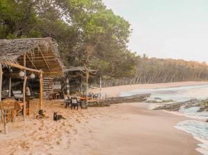 a beach with a hut and chairs on the sand at Villa Rukaththana UNAKURUWA in Tangalle