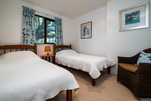 a bedroom with two beds and a chair and a window at Little Trig in Padstow