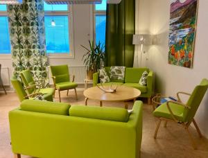 a living room with green couches and a table and chairs at Kuttainen Lodge in Karesuando