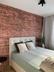 a bedroom with a brick wall and a bed at Juuri valmistunut kaksio upealla Logomon alueella. in Turku
