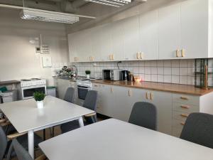 a kitchen with white cabinets and tables and chairs at Kuttainen Lodge in Karesuando