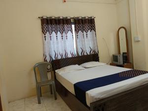 a bedroom with a bed and a chair and a window at Bhavani Residency in Dapoli