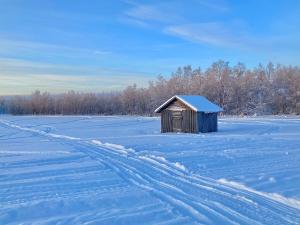 a smallshed sitting in a field covered in snow at Kuttainen Lodge in Karesuando