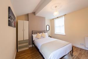 a bedroom with a bed with white sheets and a window at Holly Room in Liverpool