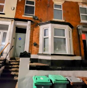 a house with two green trash cans in front of it at MM Sure Stay Accommodation - NG1 in Nottingham