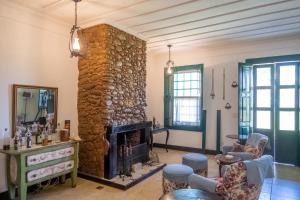 a living room with a stone fireplace and chairs at Sítio Paraíso Beach Tennis in Vassouras