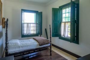 a bedroom with green windows and a bed in it at Sítio Paraíso Beach Tennis in Vassouras