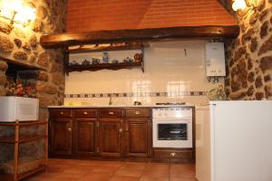 a kitchen with wooden cabinets and a white refrigerator at Casa do Balcao in Castelo Novo